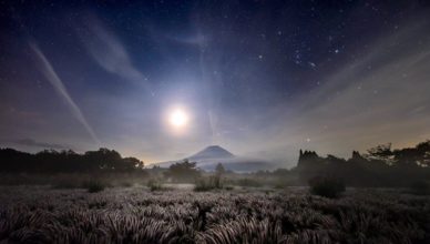 A pastagem iluminada leva a uma montanha que brilha sob a luz do luar na frente do Monte Fuji. FOTO DE TAKASHI NAKAGAWA, NATIONAL GEOGRAPHIC YOUR SHOT